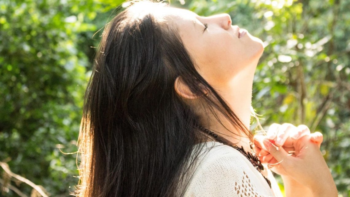 woman standing while closing her eyes and looking up
