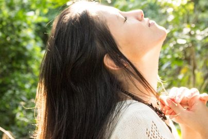 woman standing while closing her eyes and looking up